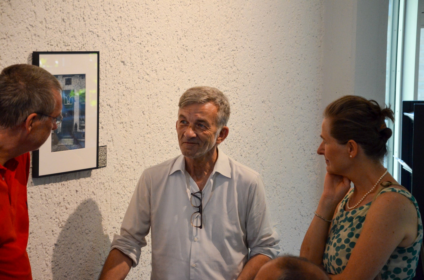 Gespräch bei der Ausstellungseröffnung vor gerahmten historischen Fotografien.
